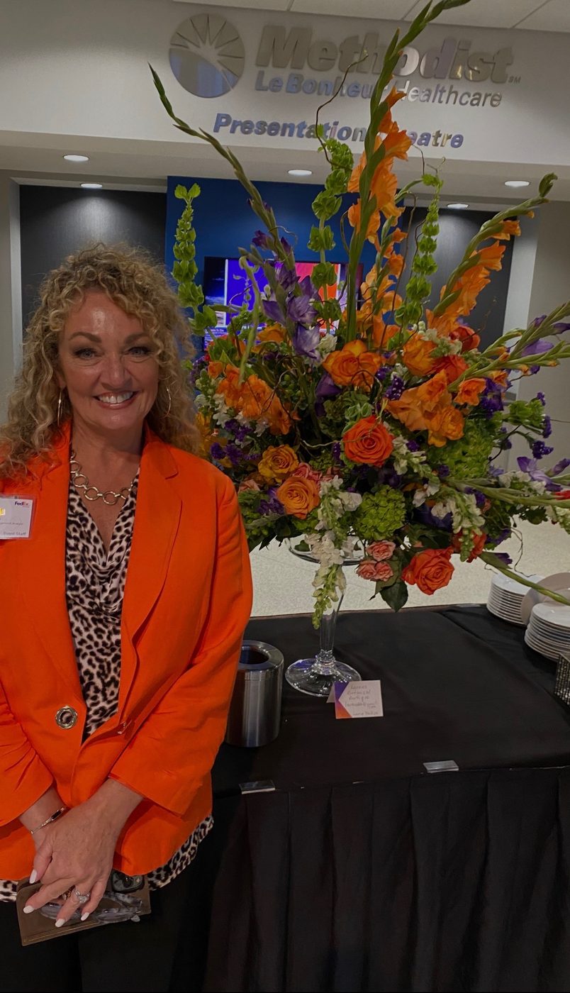 Laurie with a vivid orange and purple gala floral arrangement
