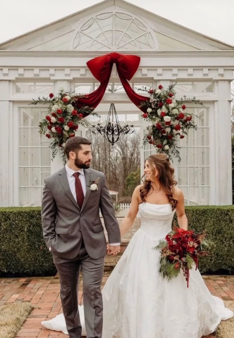 Bride and groom with red velvet bow ceremony arch